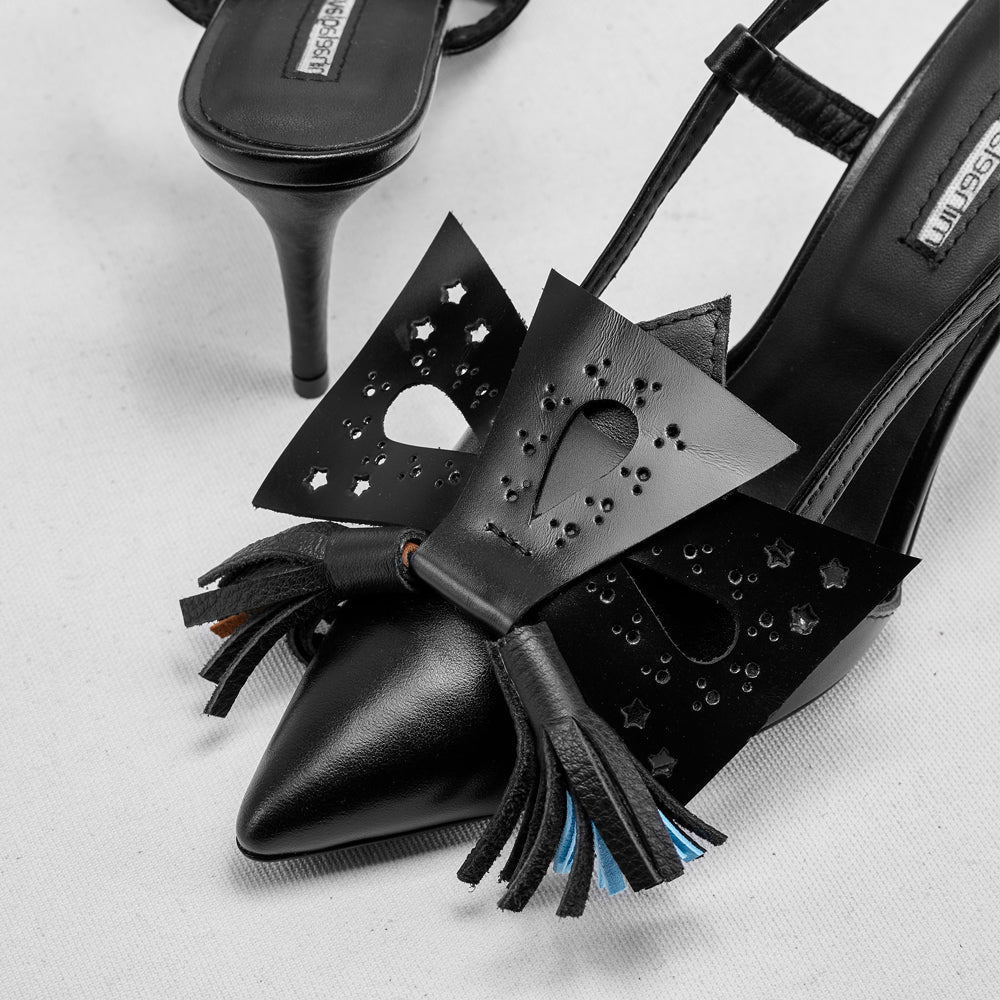 Black high-heeled shoes with star cutouts and tassels on a light gray background