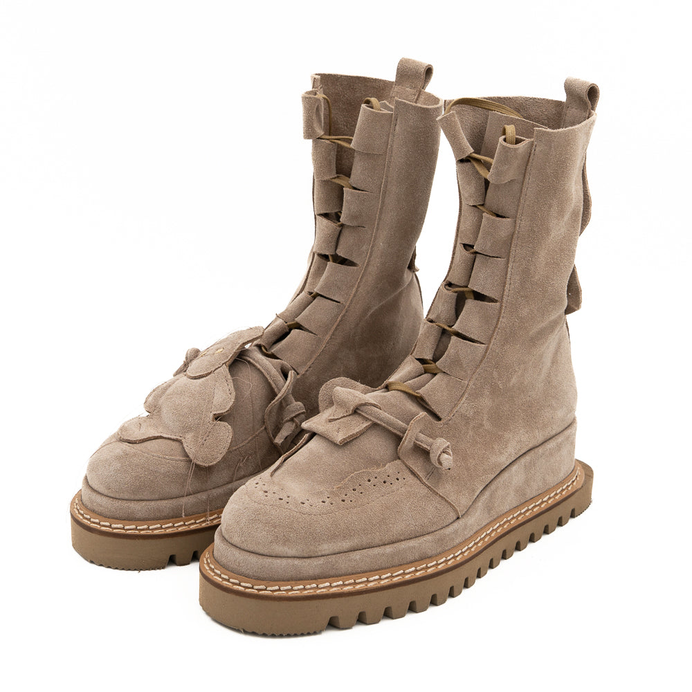 Pair of beige suede boots with laces on a white background