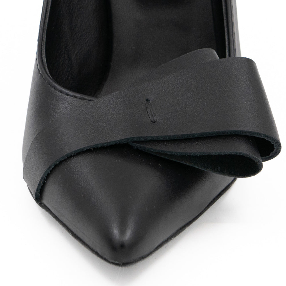 Close-up of the folded black leather bow and pointed toe on After Party pumps.