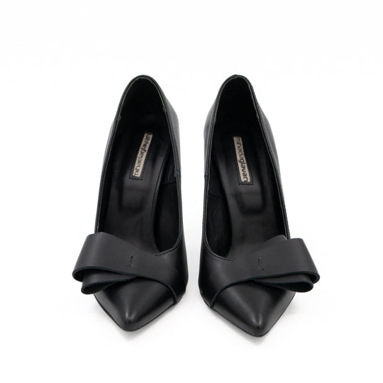 After Party black leather pumps with pointed toes and folded leather bows, front view.