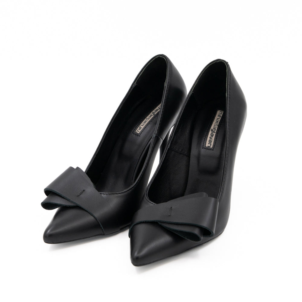 After Party black leather pumps with folded bow details and pointed toes, three-quarter view.