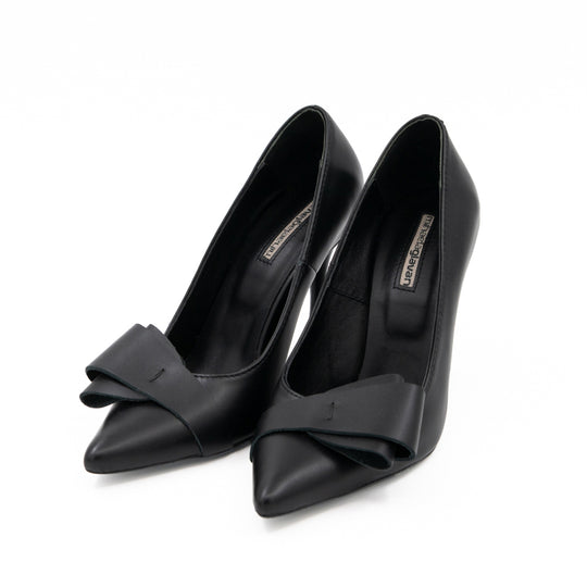 After Party black leather pumps with folded bow details and pointed toes, three-quarter view.