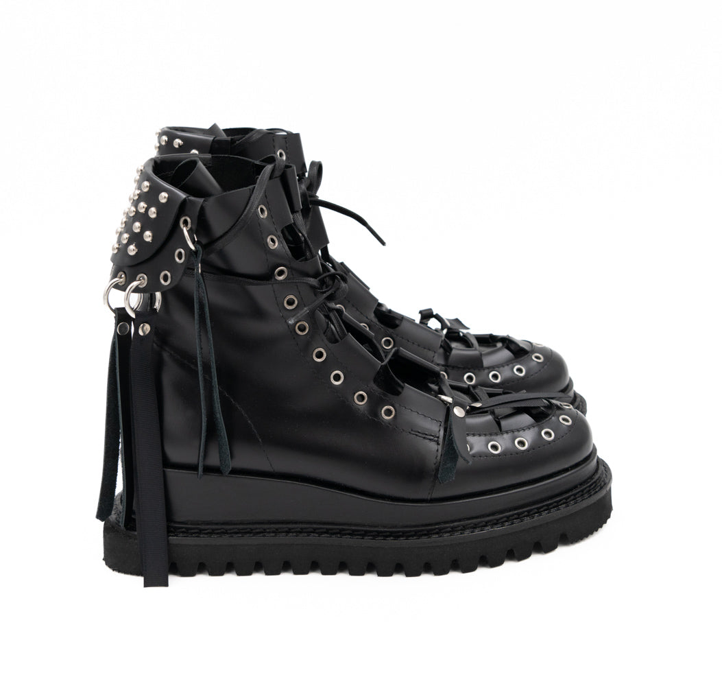 Punk Lover black leather lace-up booties by Mihaela Glavan, side view showing the studded back panel and hanging leather strips.
