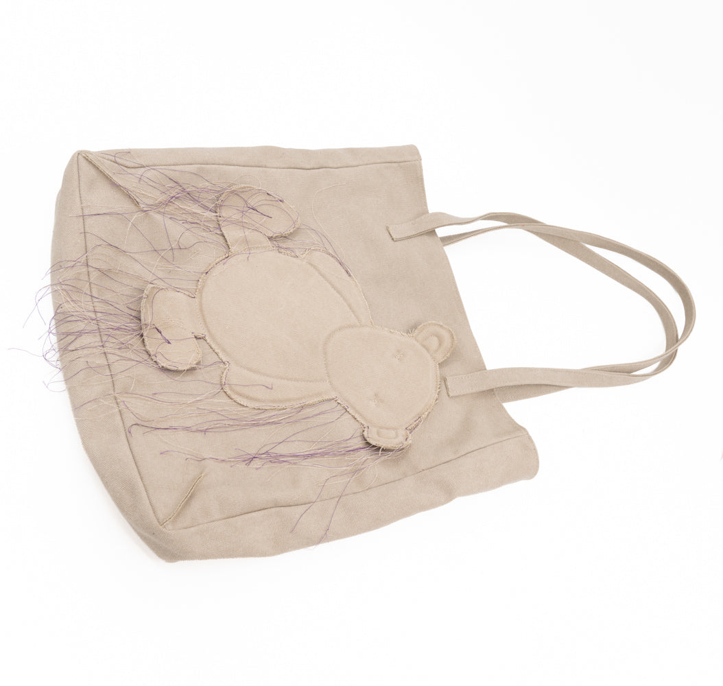 Teddy vegan beige textile totebag laid flat with shoulder handles extended and the bear applique visible.