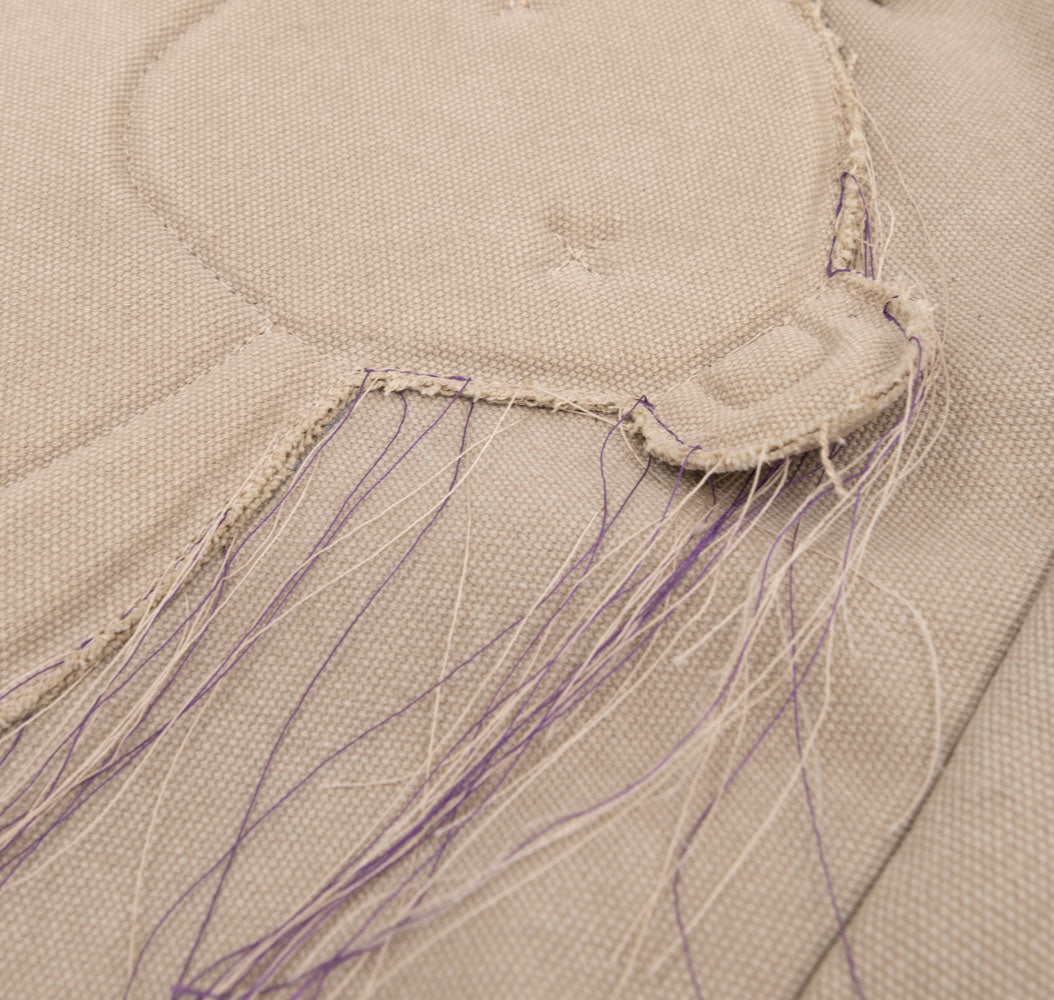Close-up of the stitched bear applique and trailing threads on the Teddy beige textile totebag.