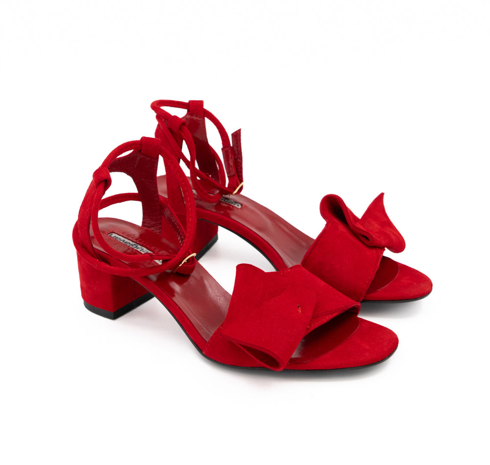 Trick Me red suede sandals, opposite three-quarter view showing the bows and gold-tone ankle buckles.