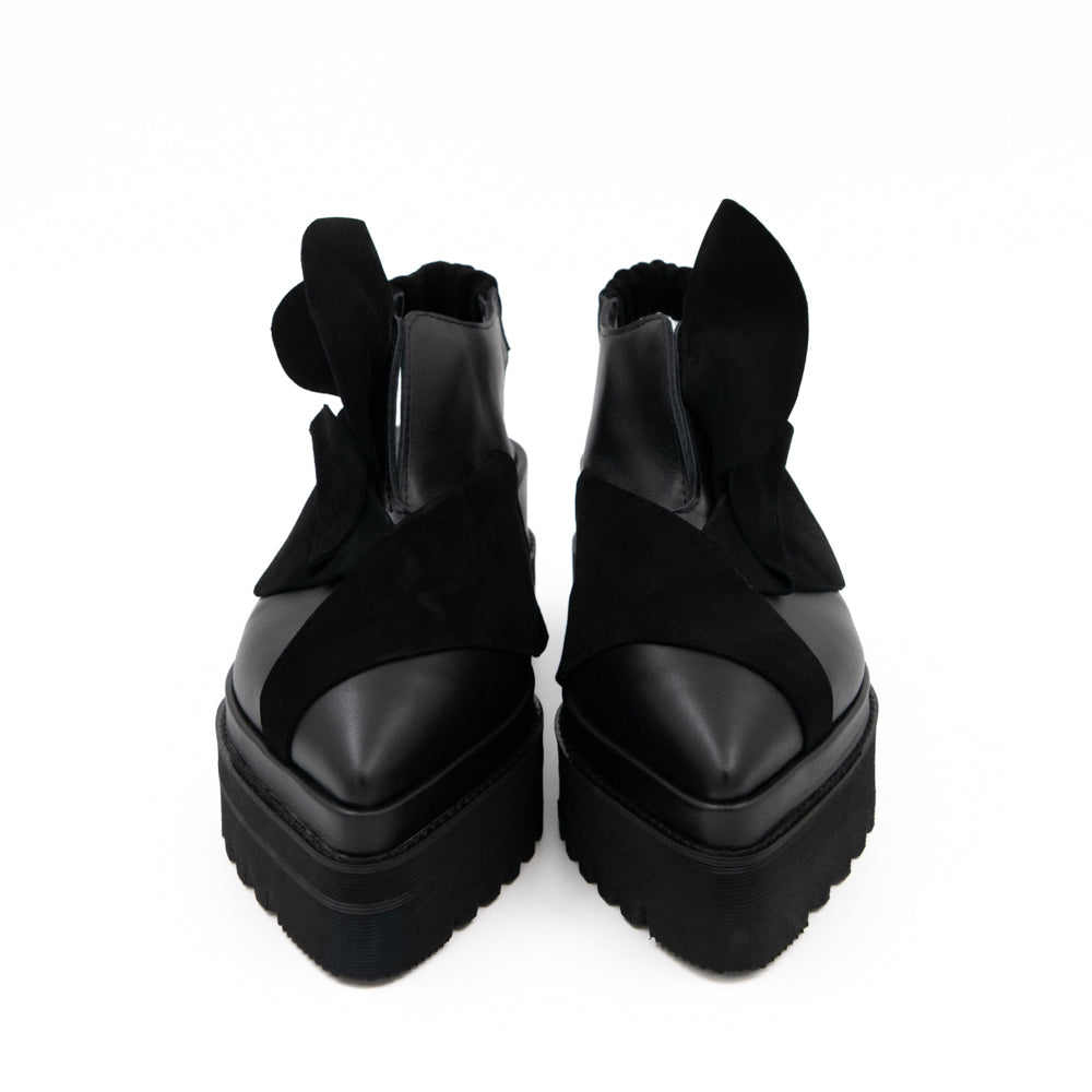 Front view of Tulips black leather open-back shoes, with pointed toes and 3D black suede petals.