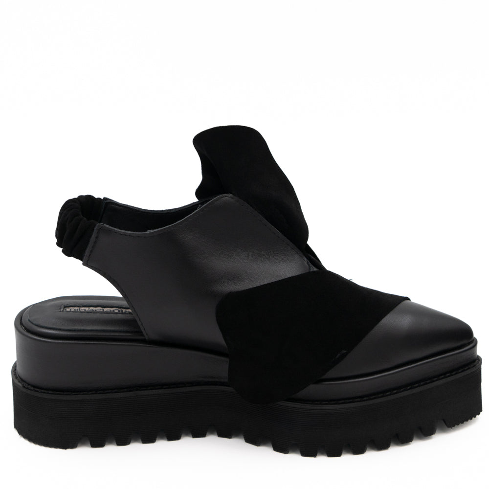 Side view of Tulips black leather open-back shoes, showing the cut-outs, elastic back strap and raised sole.
