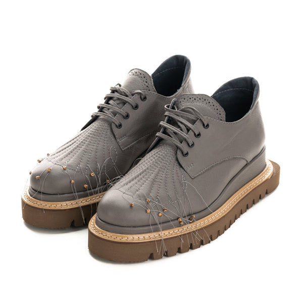 Grey leather flat shoes with natural stones details and brownie geometrical sole.