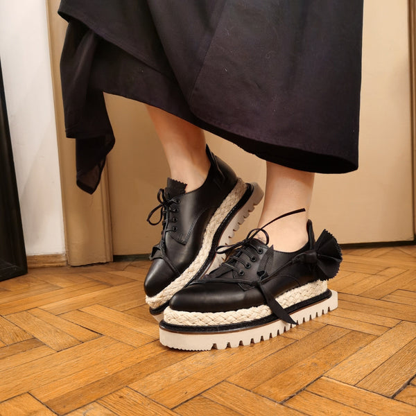 Black leather shoes with floral details and jute covered flat platform