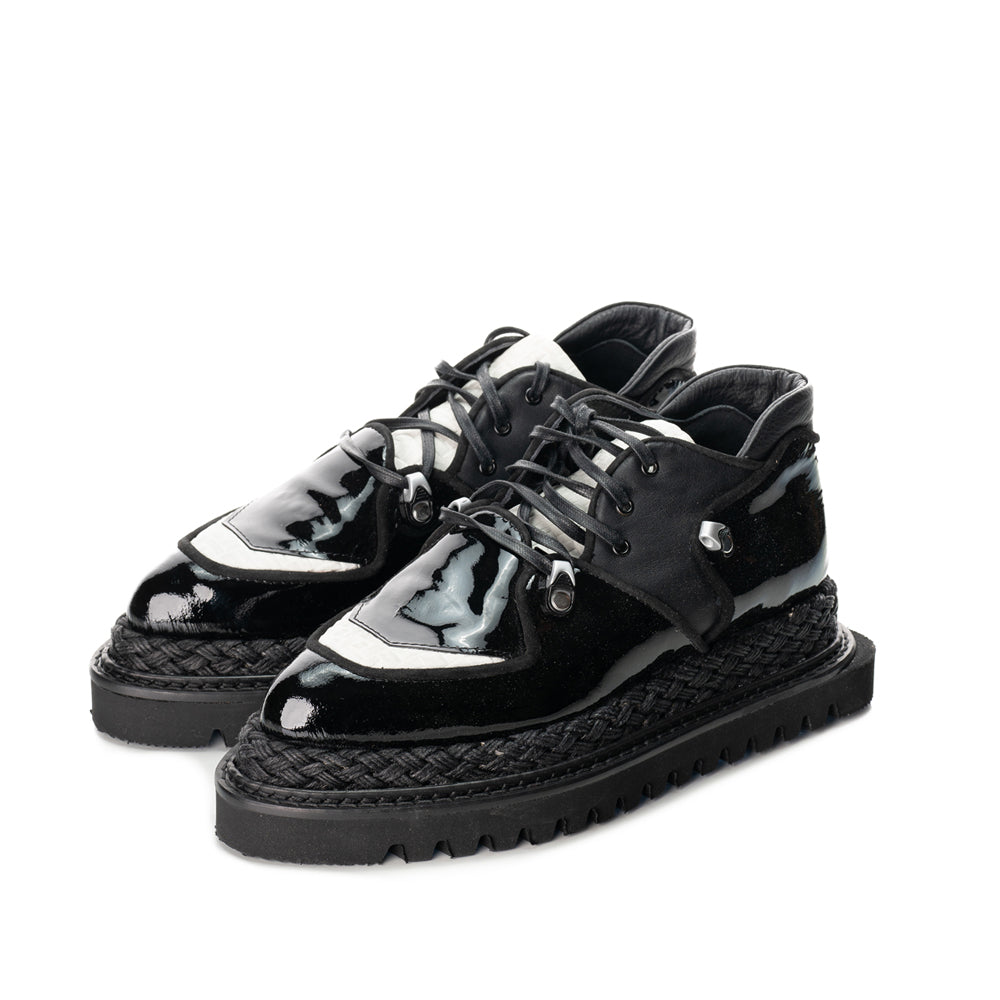 Black patent leather shoes with white textured leather details, metallic accessories and black laces